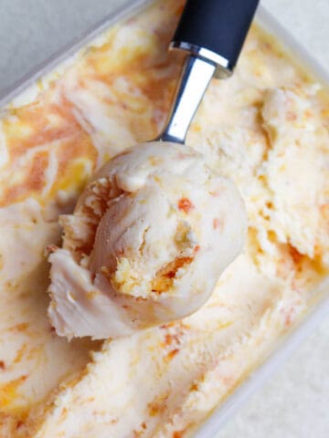 Peaches-and-cream-ice-cream-in-a-tub-with-ice-cream-scoop.