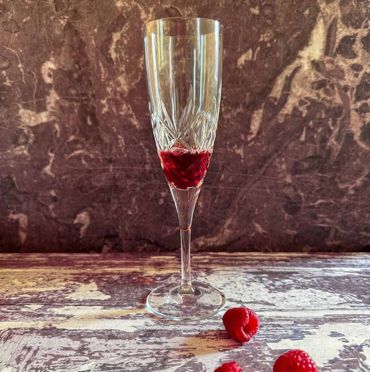 A champagne flute with a small amount of creme de cassis in the bottom. 