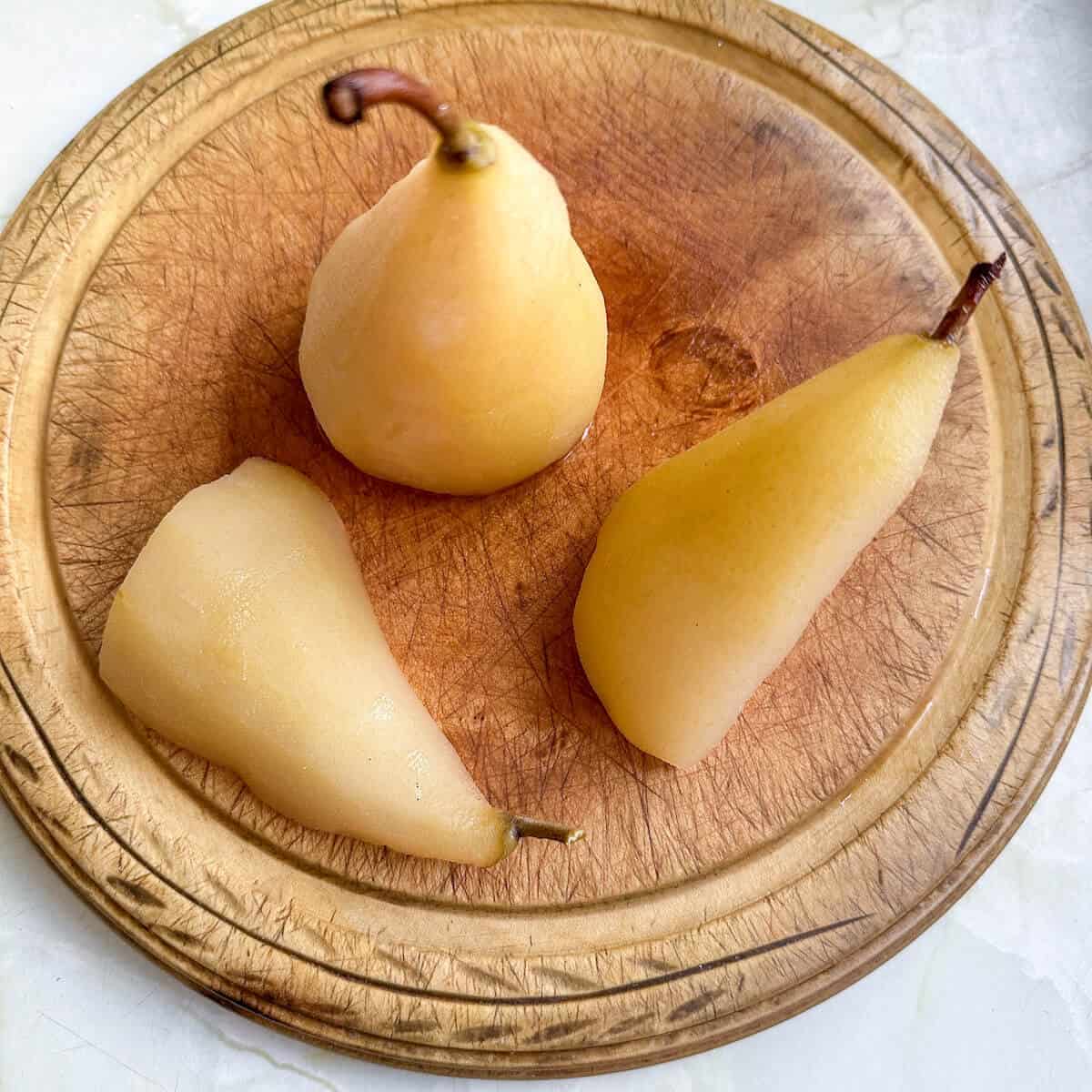 Poached pears in wine on a chopping board. 