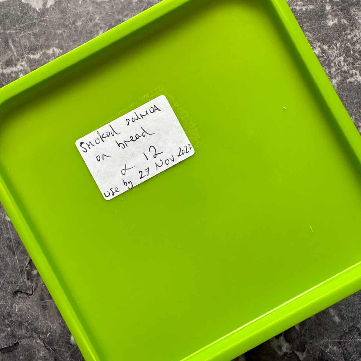 A Tupperware container with a hand written freezer label to show the contents and 'use by' date. 