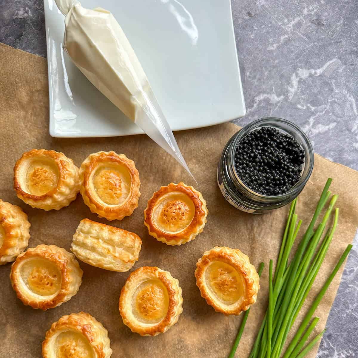 Puff pastry vol au vents, chives, caviar and creme fraiche on a worktop. 