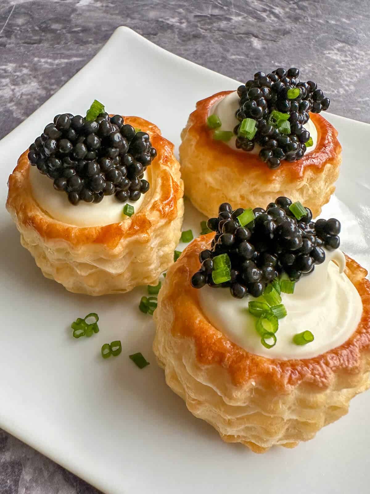 Crispy puff pastry vol au vents filled with creme fraiche and caviar and covered in chopped chives. 
