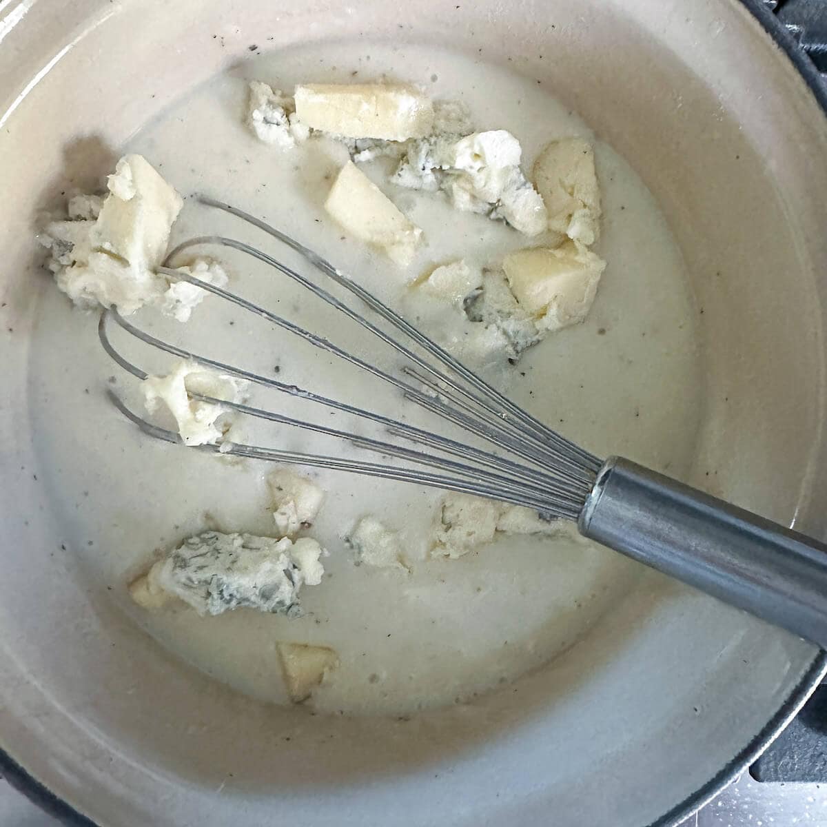 Gorgonzola cheese chunks being melted into the white sauce for leeks. 