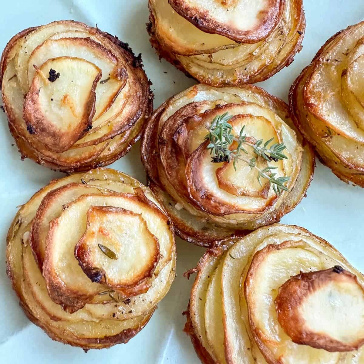 Crispy potato roses with fresh thyme garnish on a serving plate. 