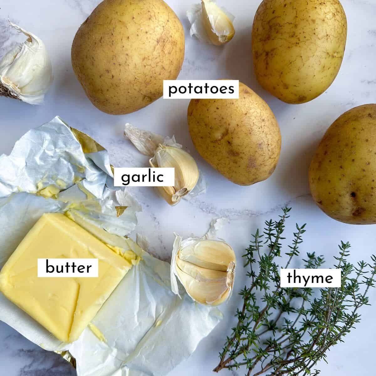 Potatoes, butter, thyme and garlic on a worktop. 