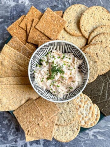 Easy smoked salmon dip in a bowl surrounded by crackers.