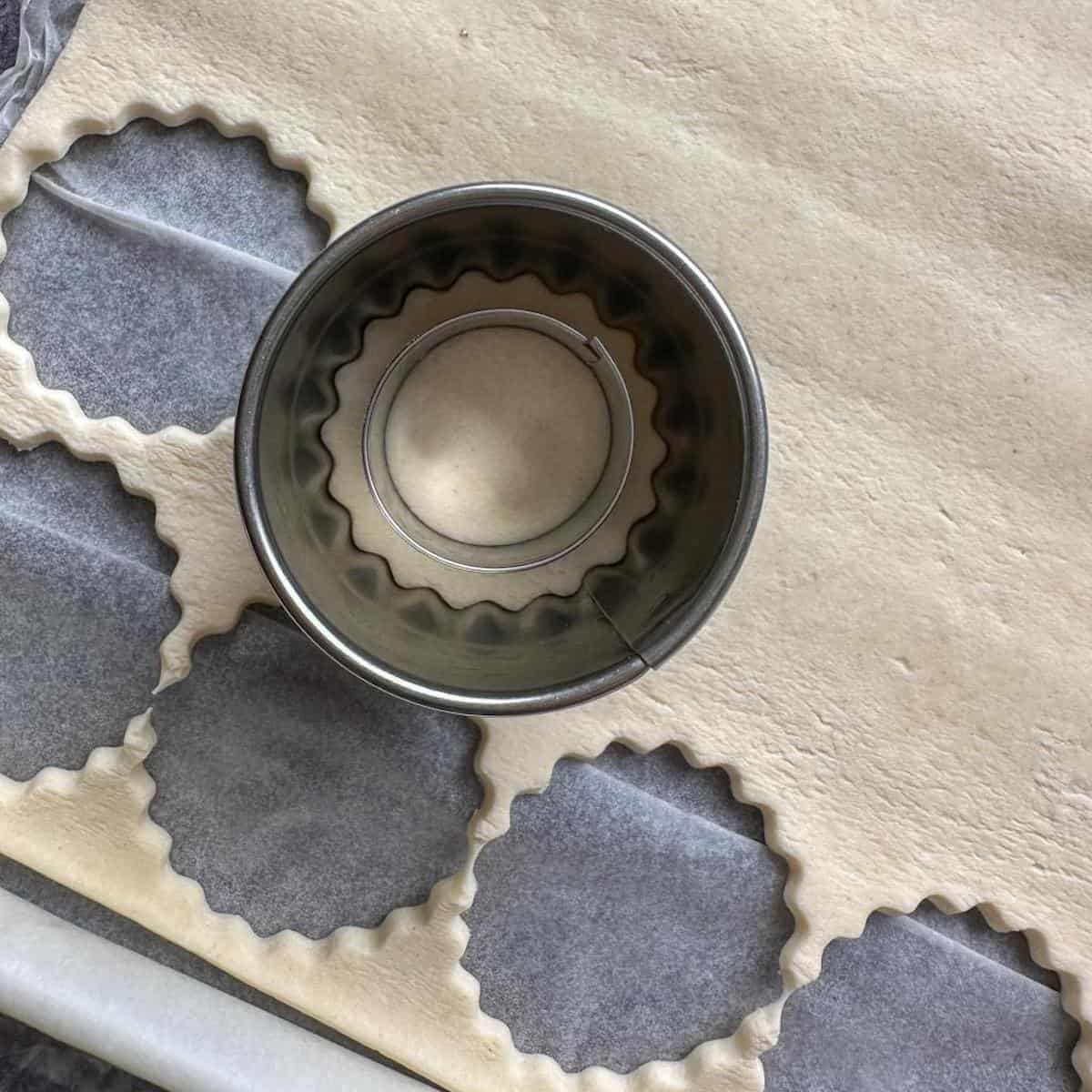 A sheet of puff pastry with cookie cutters on top.
