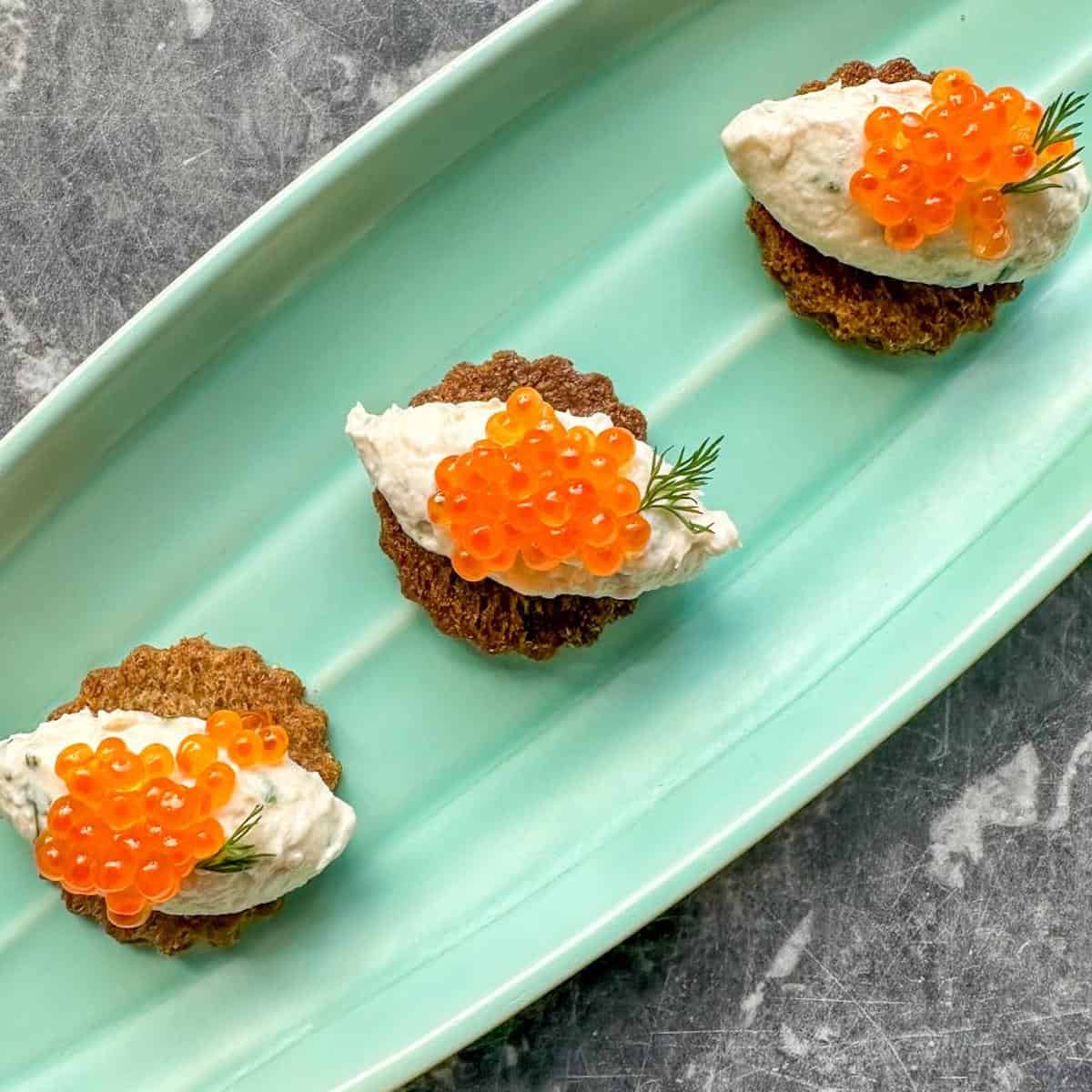 Salmon roe canapes garnished with fresh dill on a platter. 