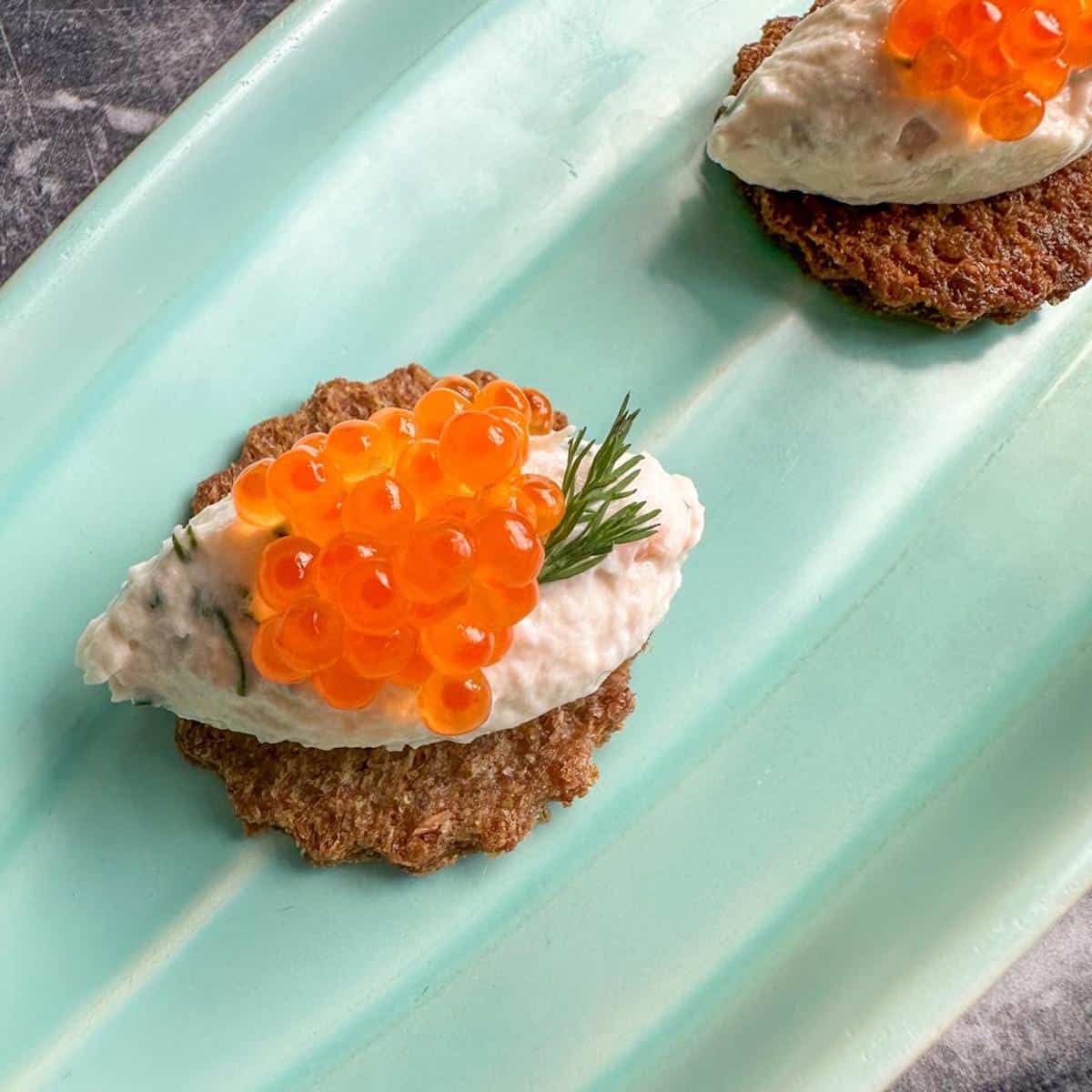 A quenelle of smoked salmon mousse on a canape base topped with salmon roe.