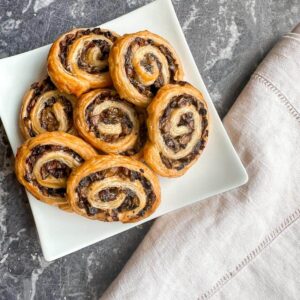Truffle porcini mushroom puff pastry pinwheels on a serving plate with a napkin.