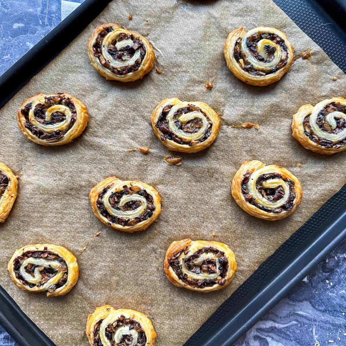 Baked pinwheel appetizers on a baking tray.