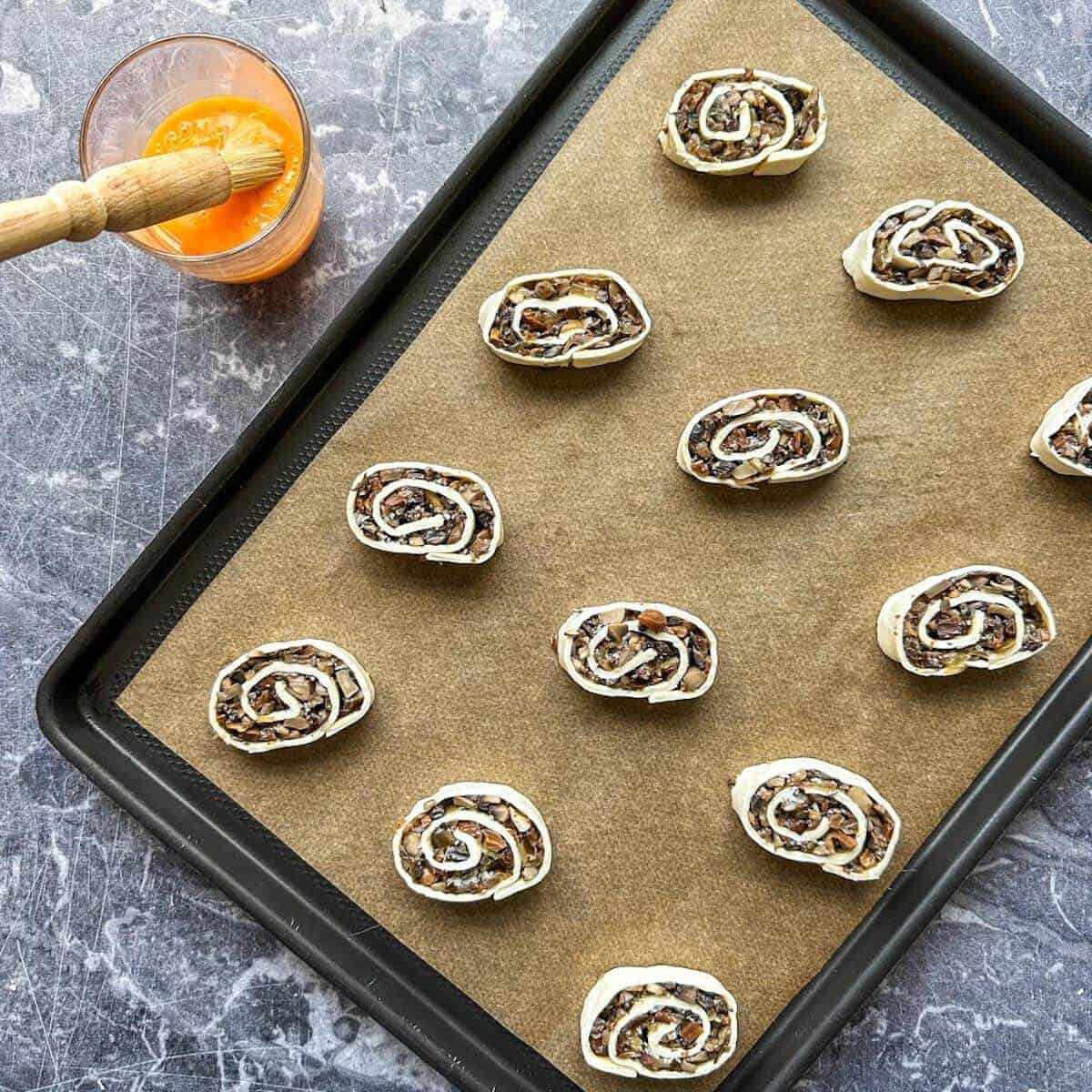 A tray of mushroom puff pastry pinwheels about to be egg washed and baked. 