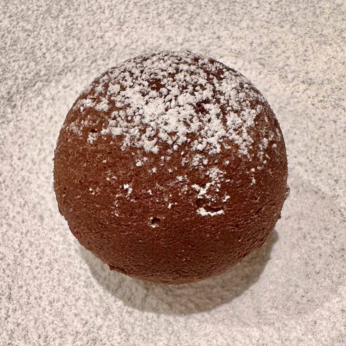 A chocolate truffle torte bomb on a plate dusted with powdered sugar. 
