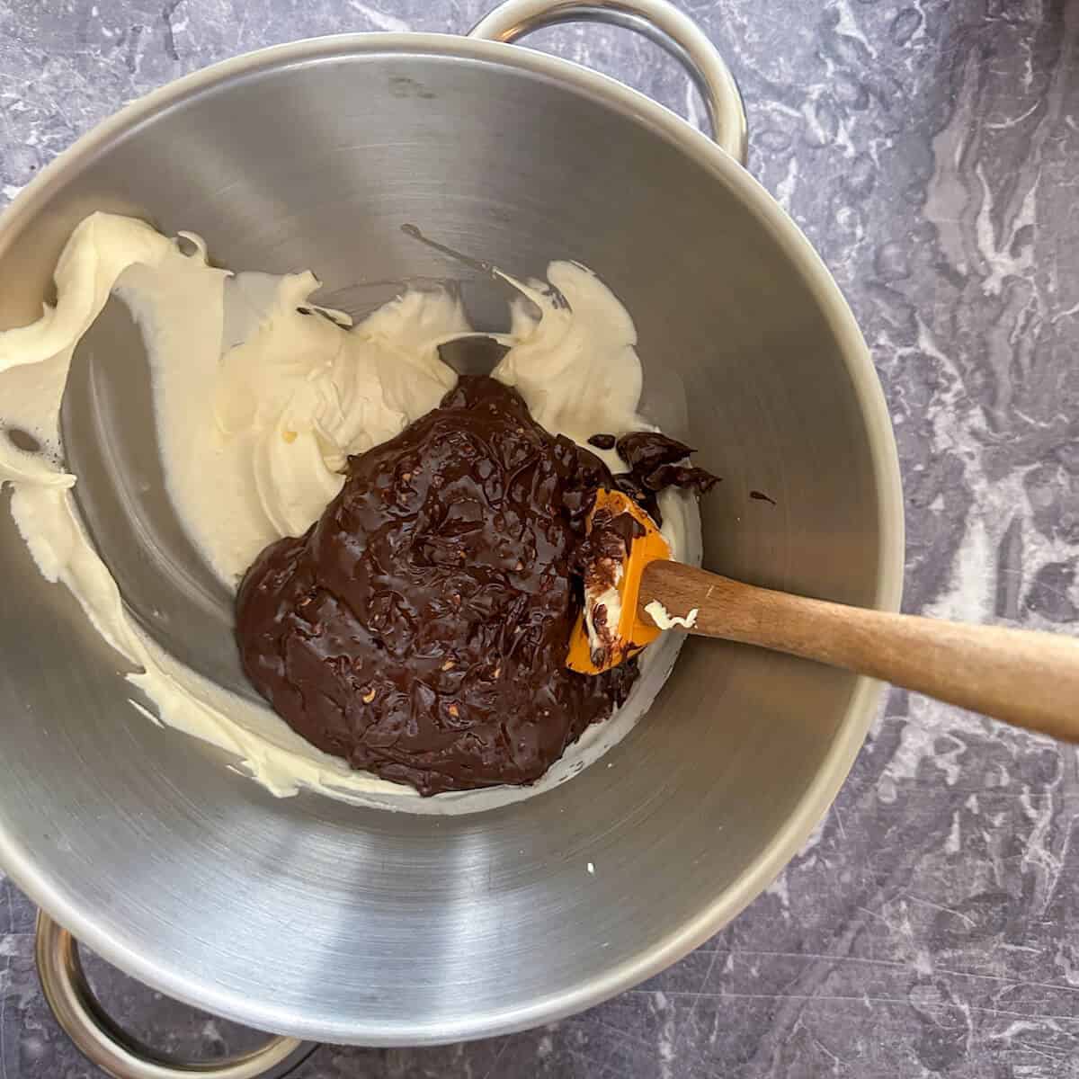 Whipped cream being folded into the chocolate mixture with a spatula. 