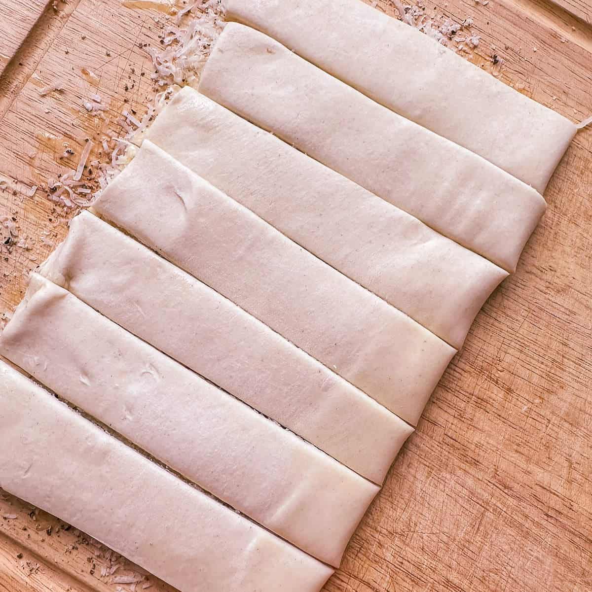 A piece of puff pastry cut into strips to make puff pastry twists. 