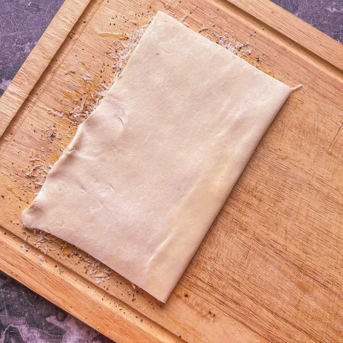 A folded piece of puff pastry with cheese and pepper inside.