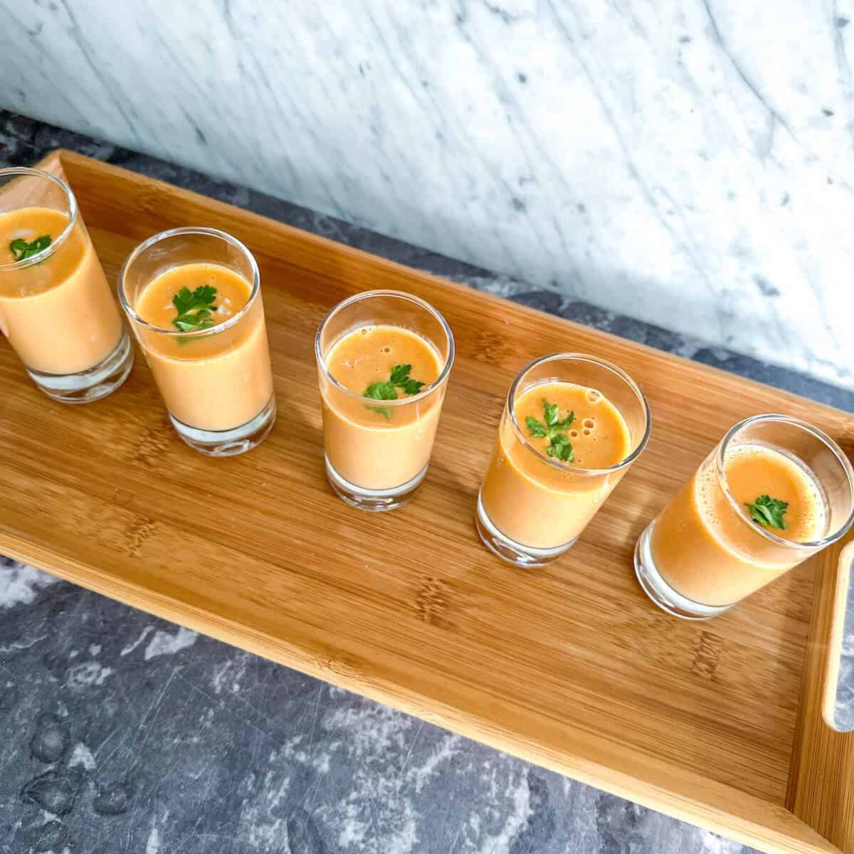 A tray holding short glasses full of crab bisque to serve as an amuse bouche. 