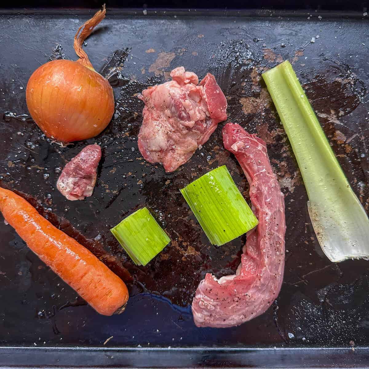 Giblets on a baking tray with onion, carrot, celery and leek. 