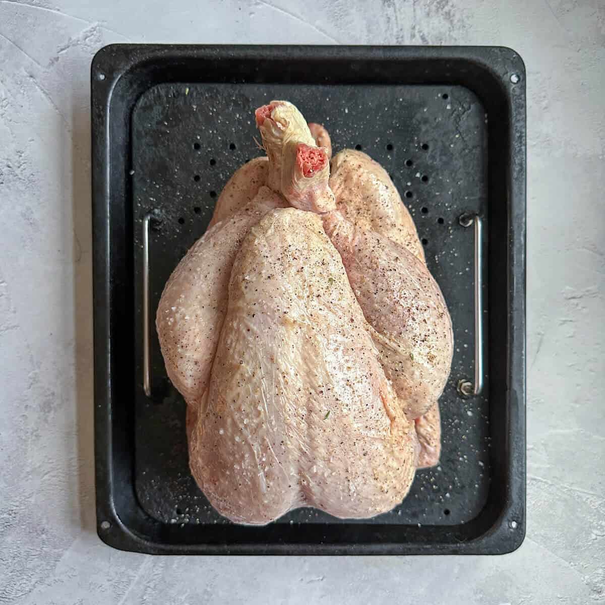 Fresh capon chicken on a roasting tray. 