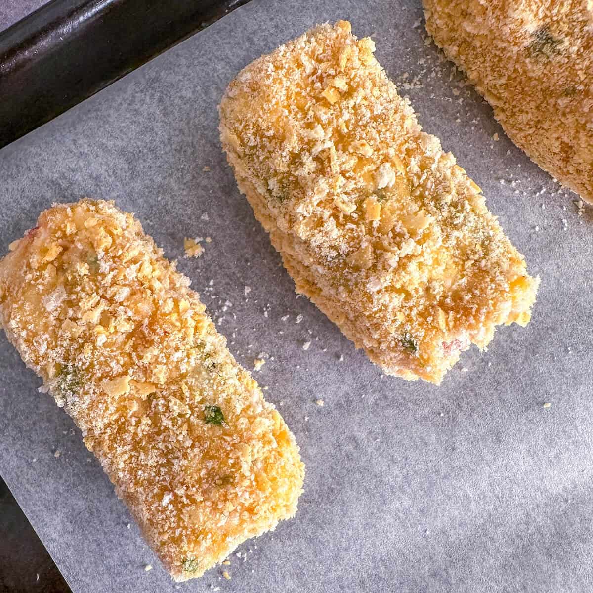 Breadcrumbed crab croquettes on a tray ready to be deep fried.