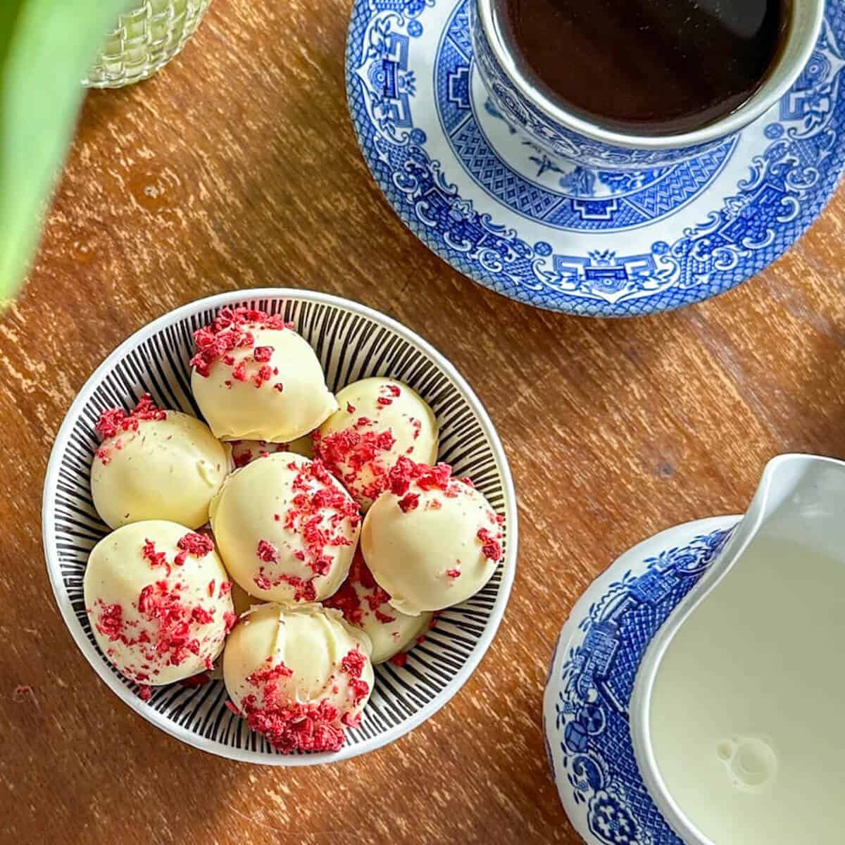 Easy Chambord Chocolate Truffles in a bowl next to a cup of coffee and jug of milk.