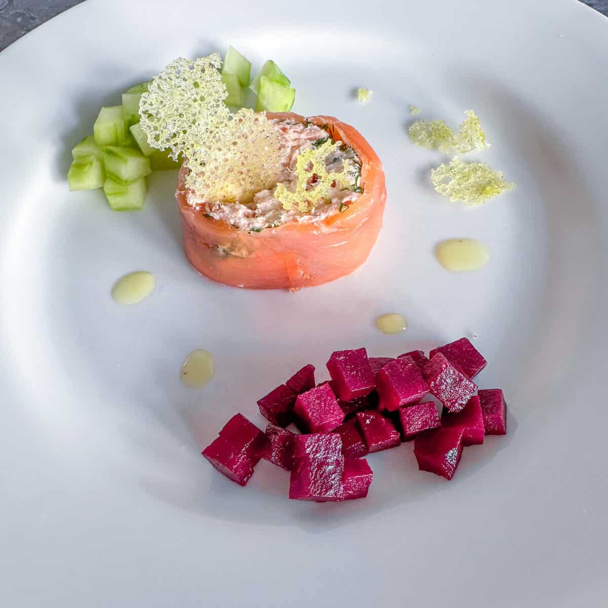 A plate with beetroot and cucumber salad and a slice of smoked salmon terrine. 