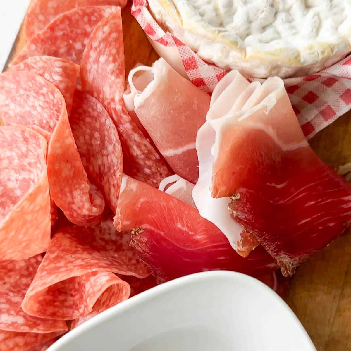 A close up of cured meats, ruffled and rolled to give texture to a grazing board. 