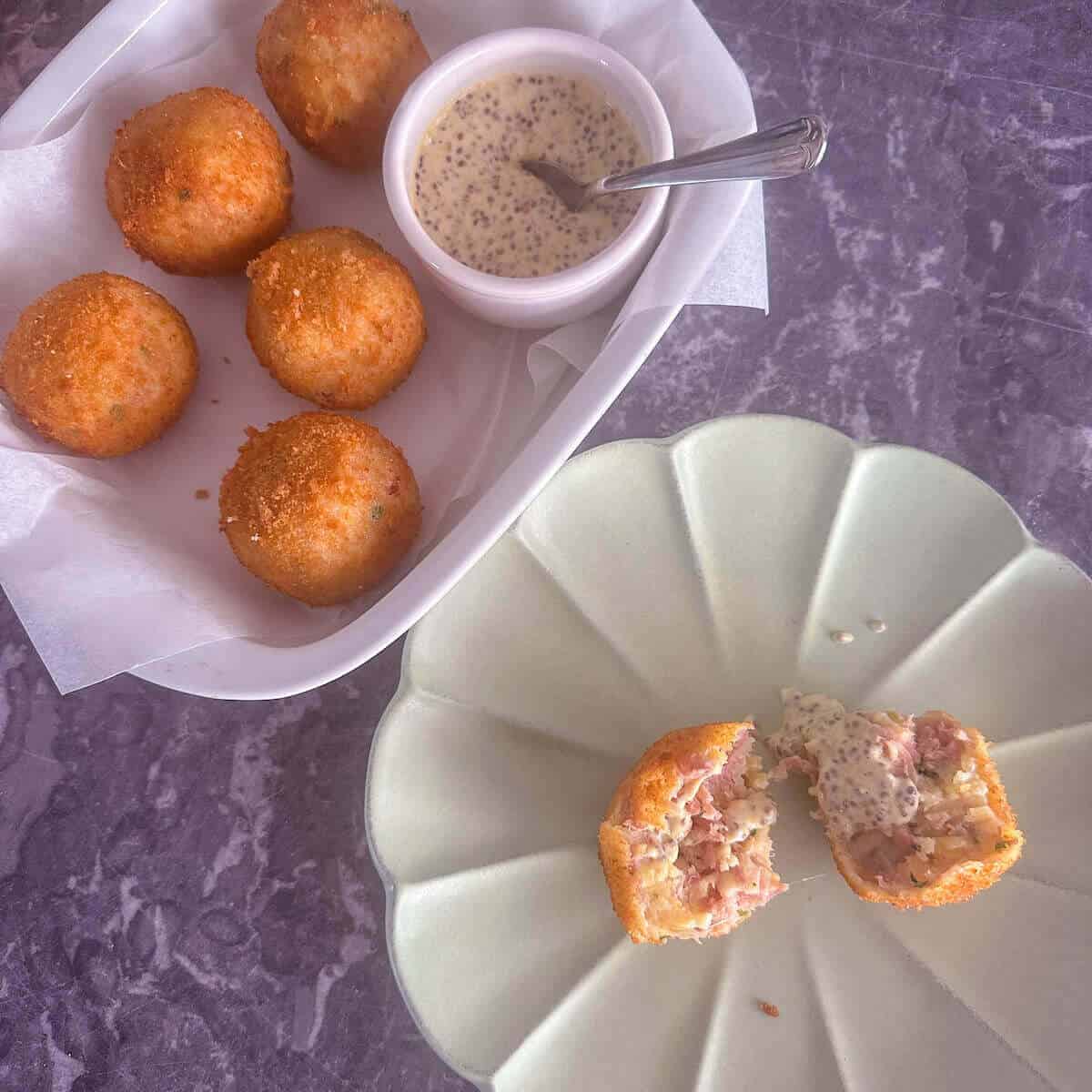 A serving of ham hock croquettes next to a serving dish with more croquettes in. 