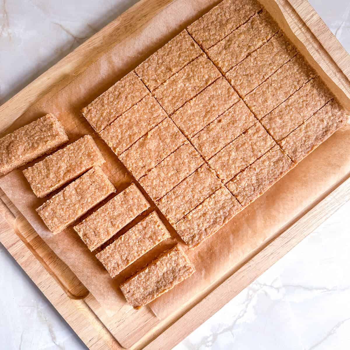 Polenta shortbread on a wooden board being cut up into cookies. 