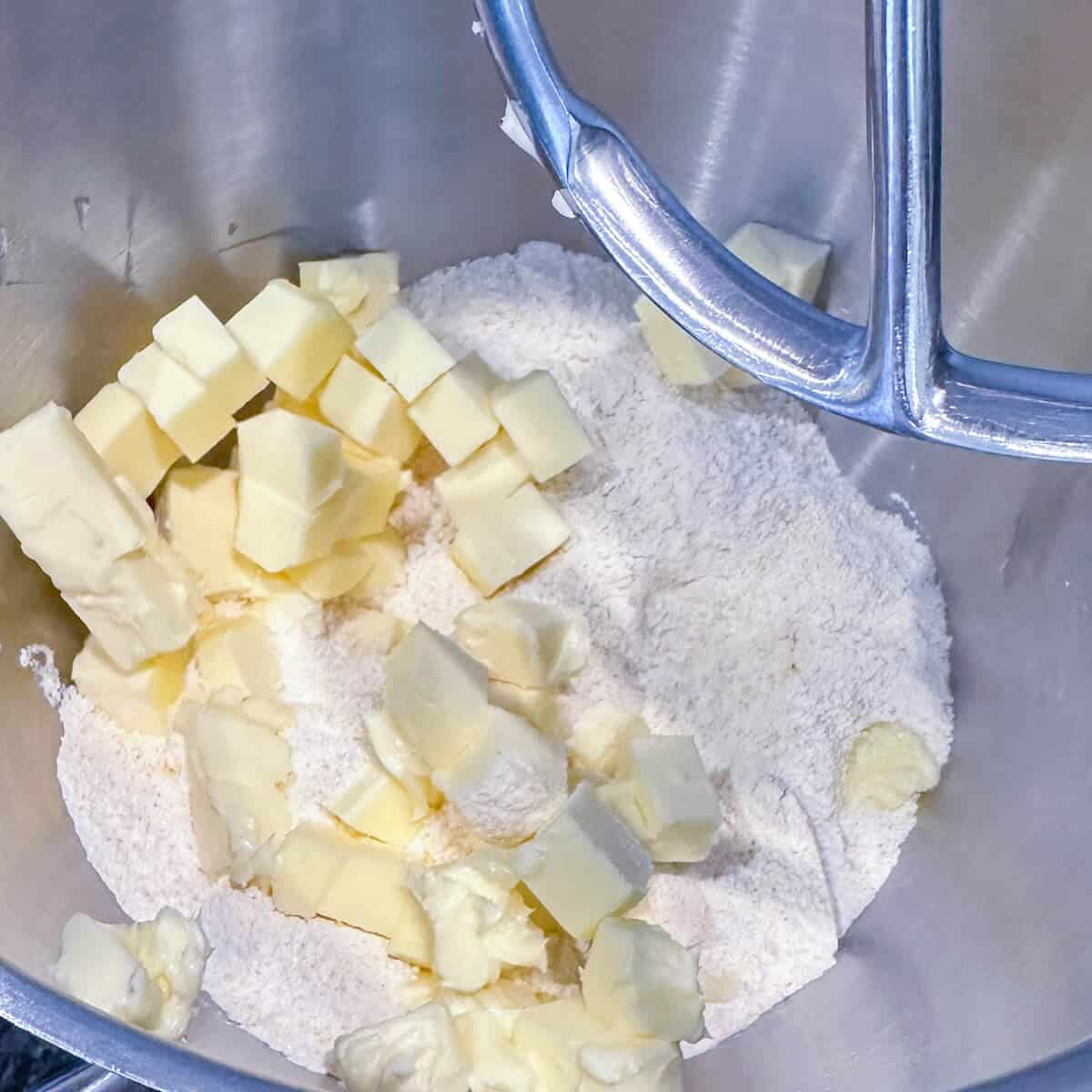 Cubes of soft butter in the bowl of a stand mixer with flour, polenta flour and sugar. 