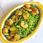 A dish of warm potato asparagus salad with peas and a dill vinaigrette dressing.