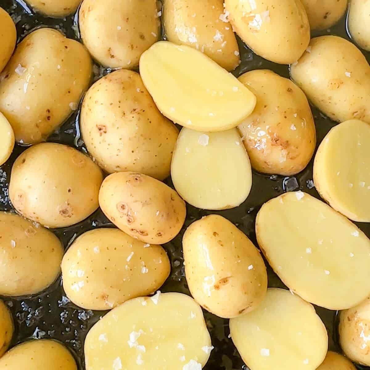 Sliced potatoes on a baking tray with salt. 