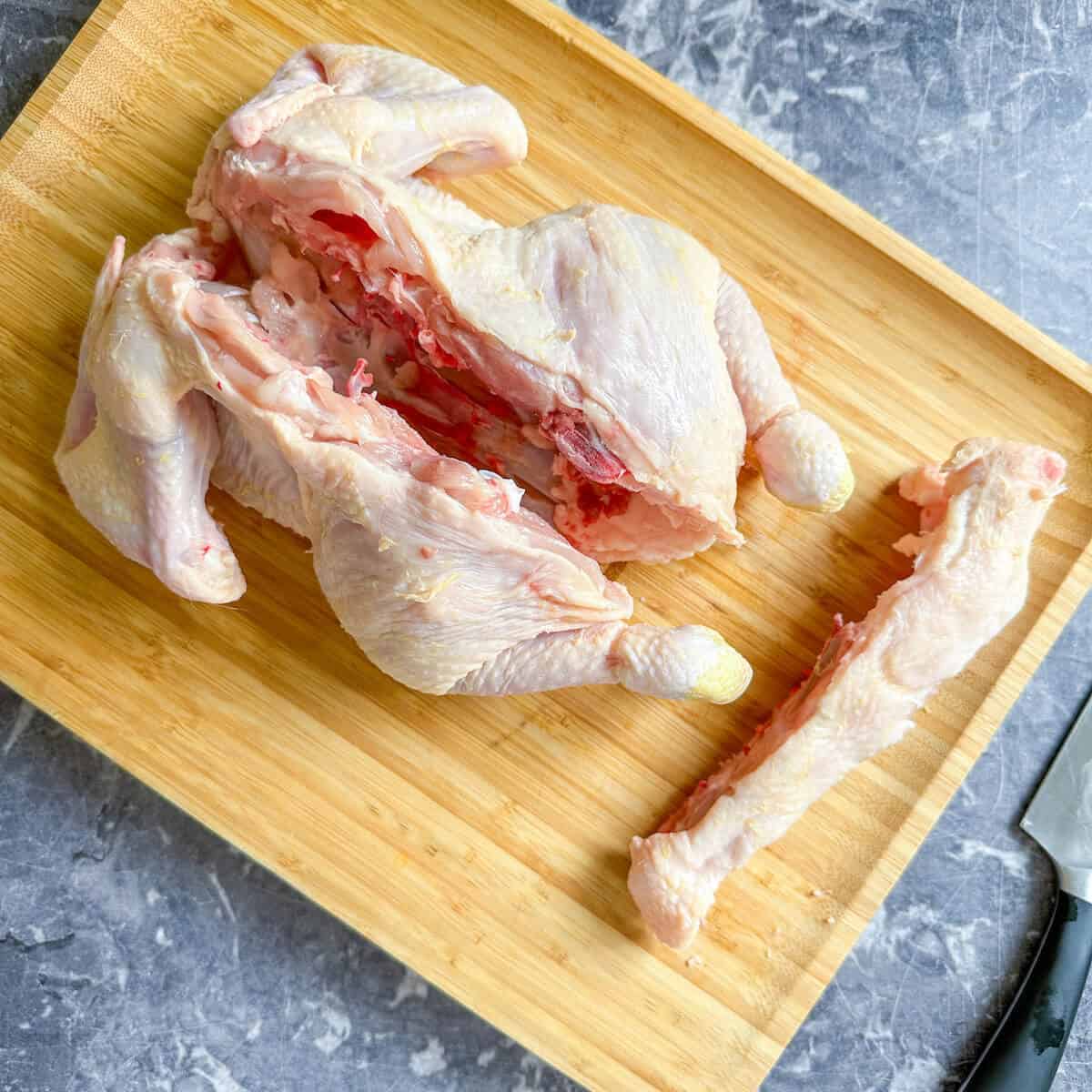 A chicken on a chopping board with its backbone removed. 