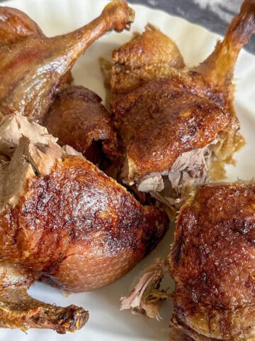 A whole roasted duck carved into portions on a serving plate.