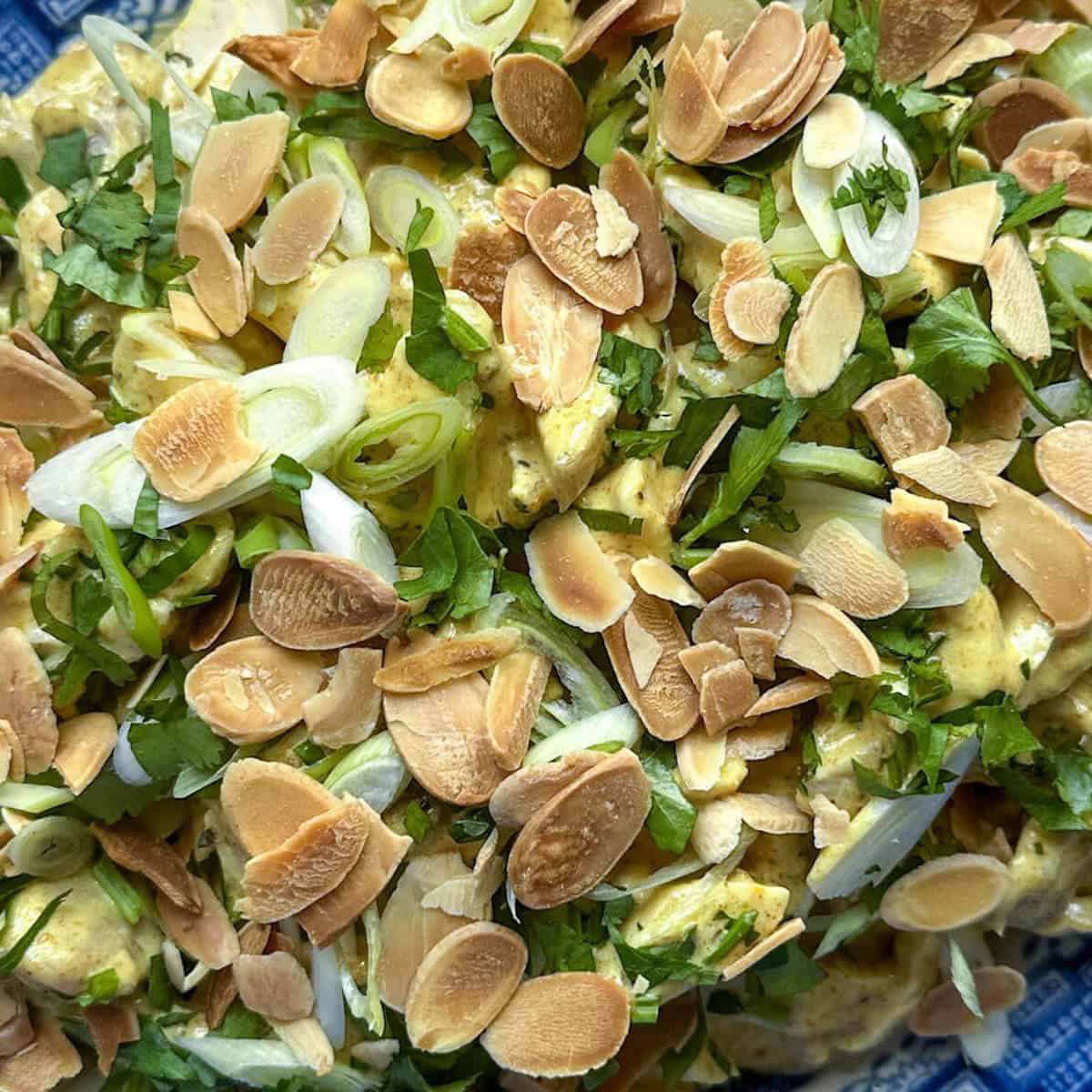 Coronation chicken salad garnished with toasted flaked almonds, spring onion and coriander leaves.