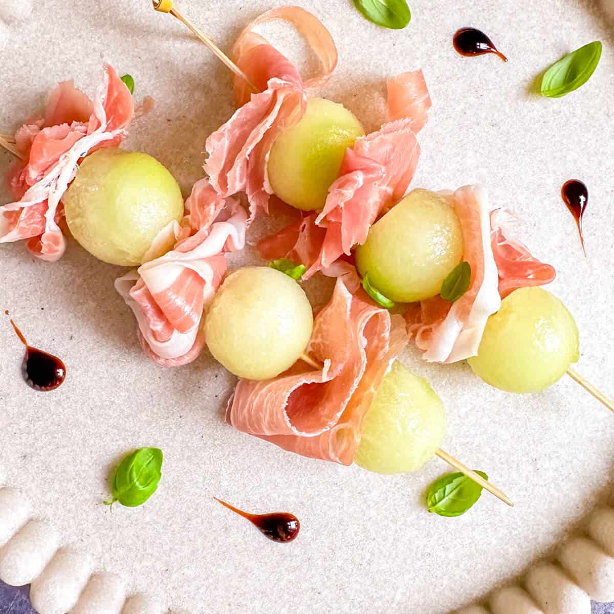 A plate of melon prosciutto skewers with balsamic glaze. 