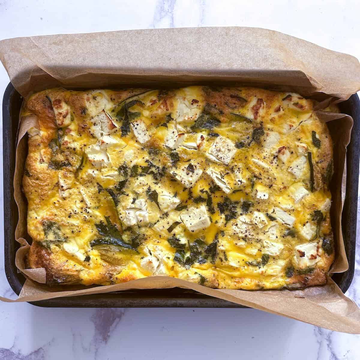 A tray of freshly baked frittata with feta, courgette and fresh mint.