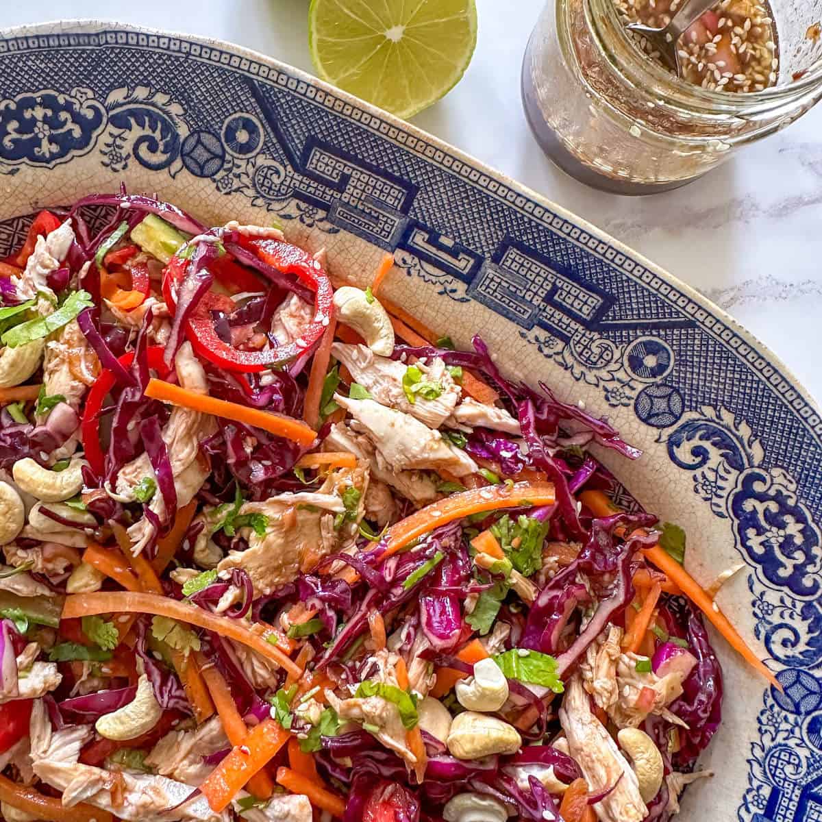 Chicken and cabbage salad with sesame seeds and a miso vinaigrette dressing on a serving platter. 