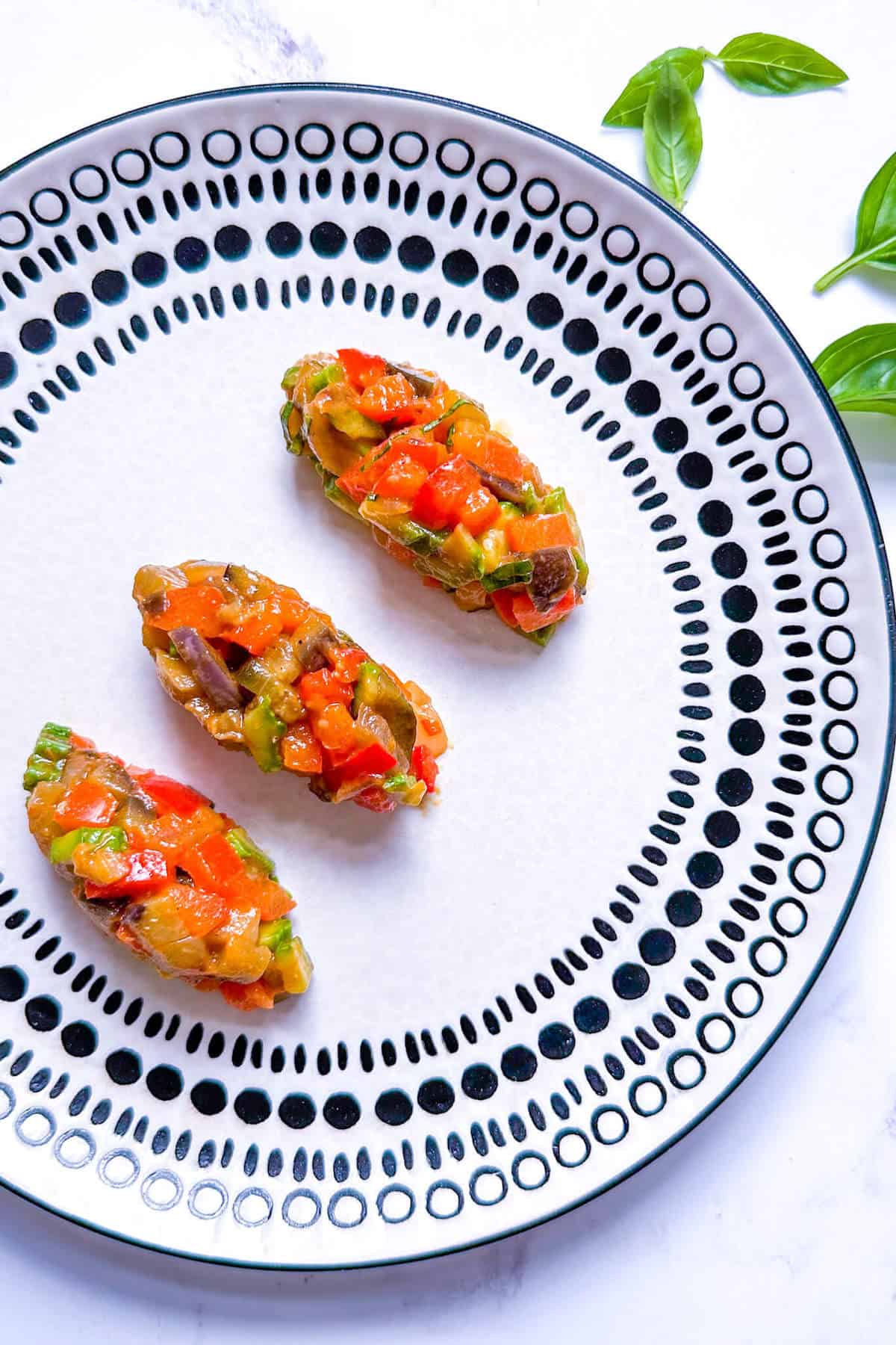 Three ratatouille quenelles on a plate.