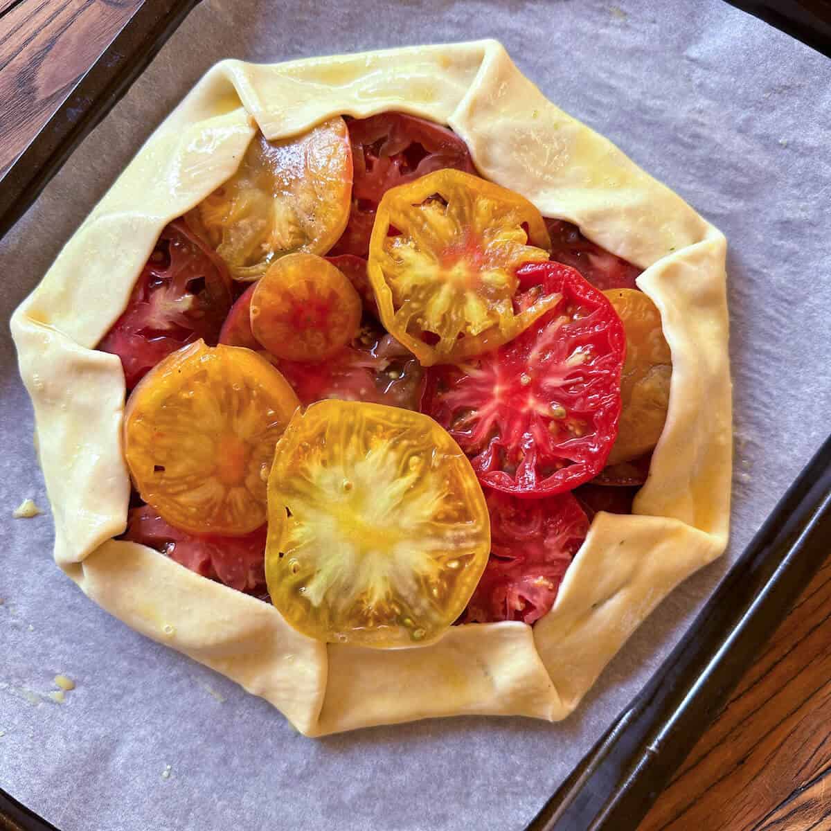 An unbaked tomato galette on a baking tray. 