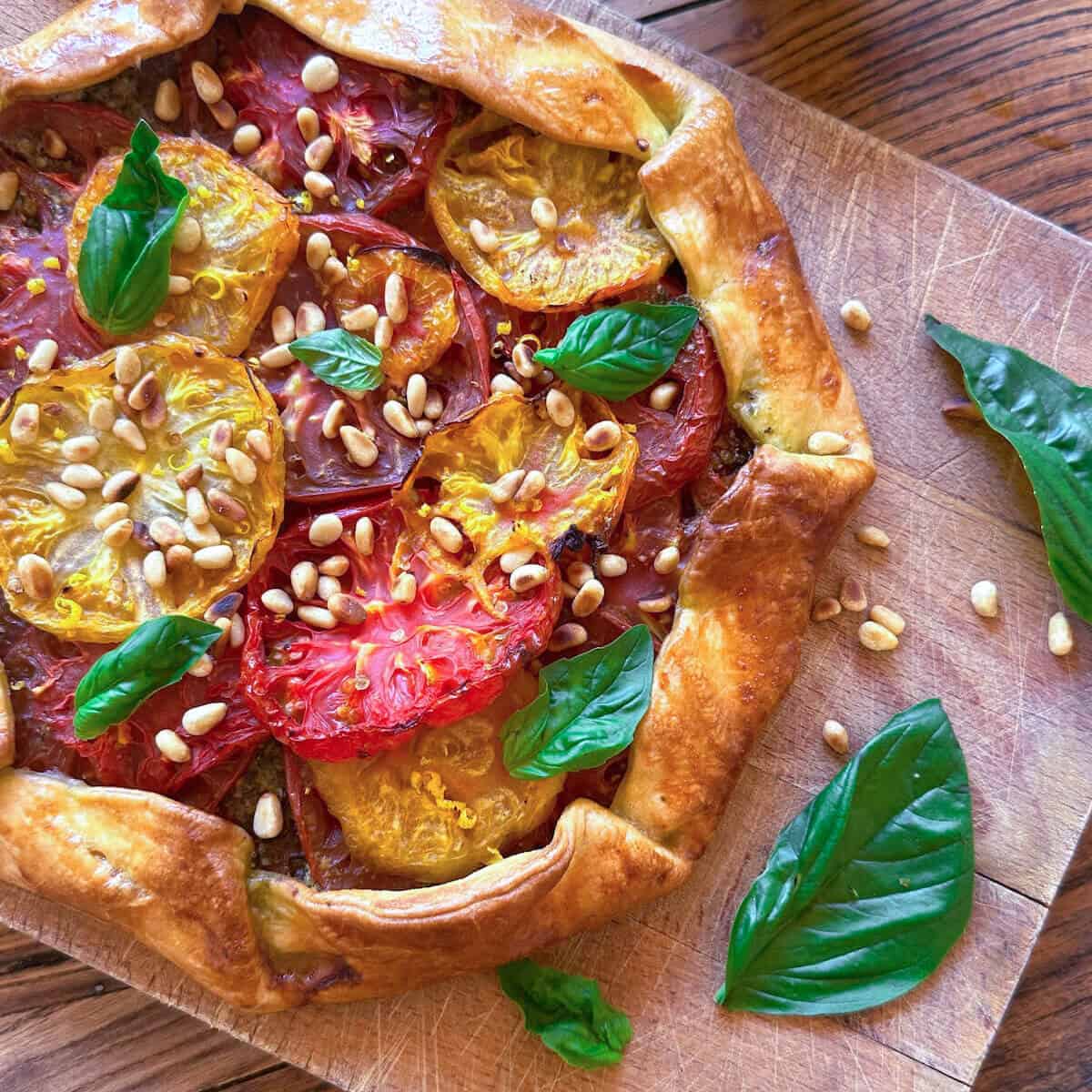 a baked tomato galette on a wooden chopping board.