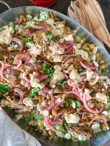 Spiced chicken shawarma salad on a bed of couscous in a serving dish.