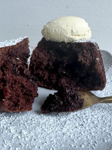 Dark chocolate sponge pudding on a plate topped with clotted cream.