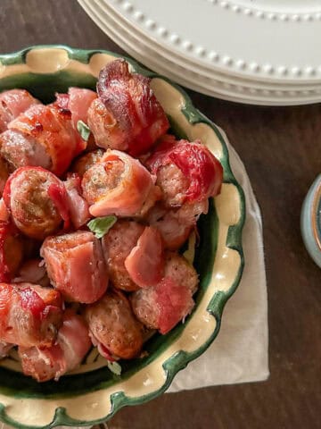 Crispy bacon wrapped sausages in a serving bowl.