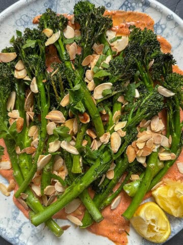 Roasted Tenderstem Broccoli Salad on a serving plate with harissa yogurt and toasted almonds.