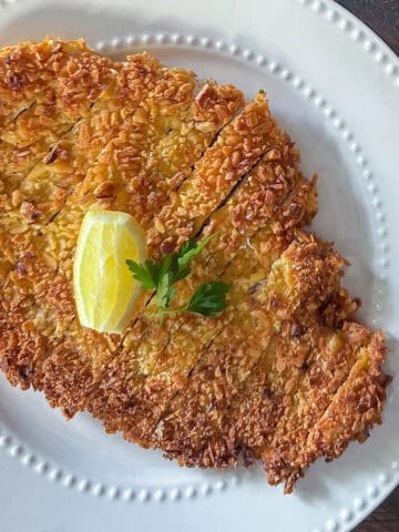 Perfectly crispy panko chicken on a plate with a slice of lemon and parsley.