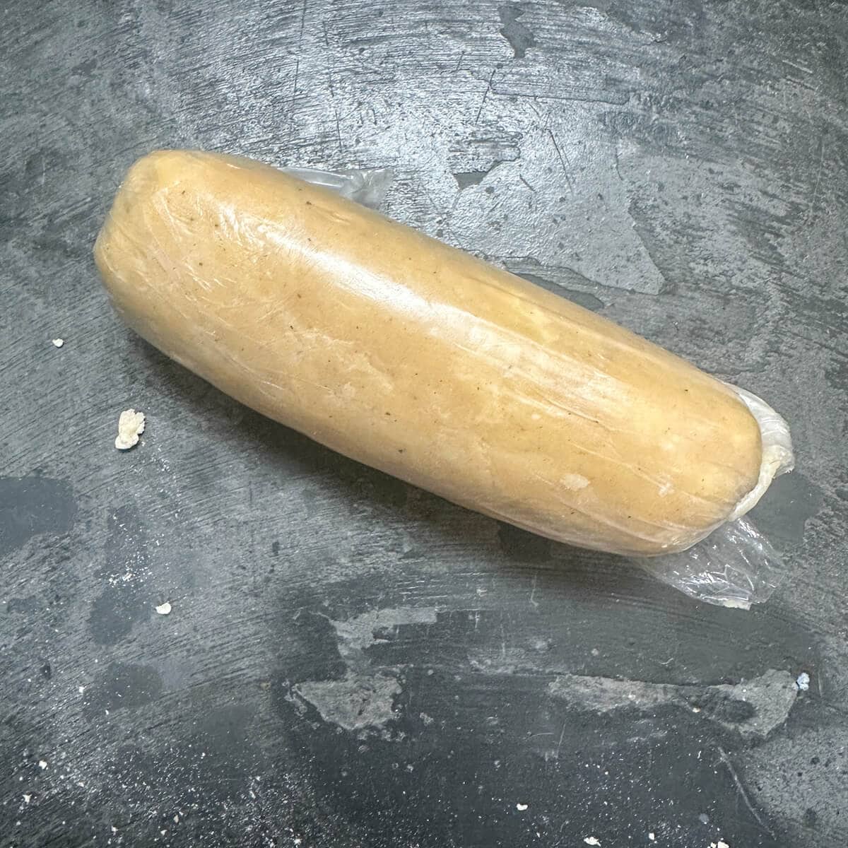 A log of parmesan sable dough wrapped in plastic food wrap. 