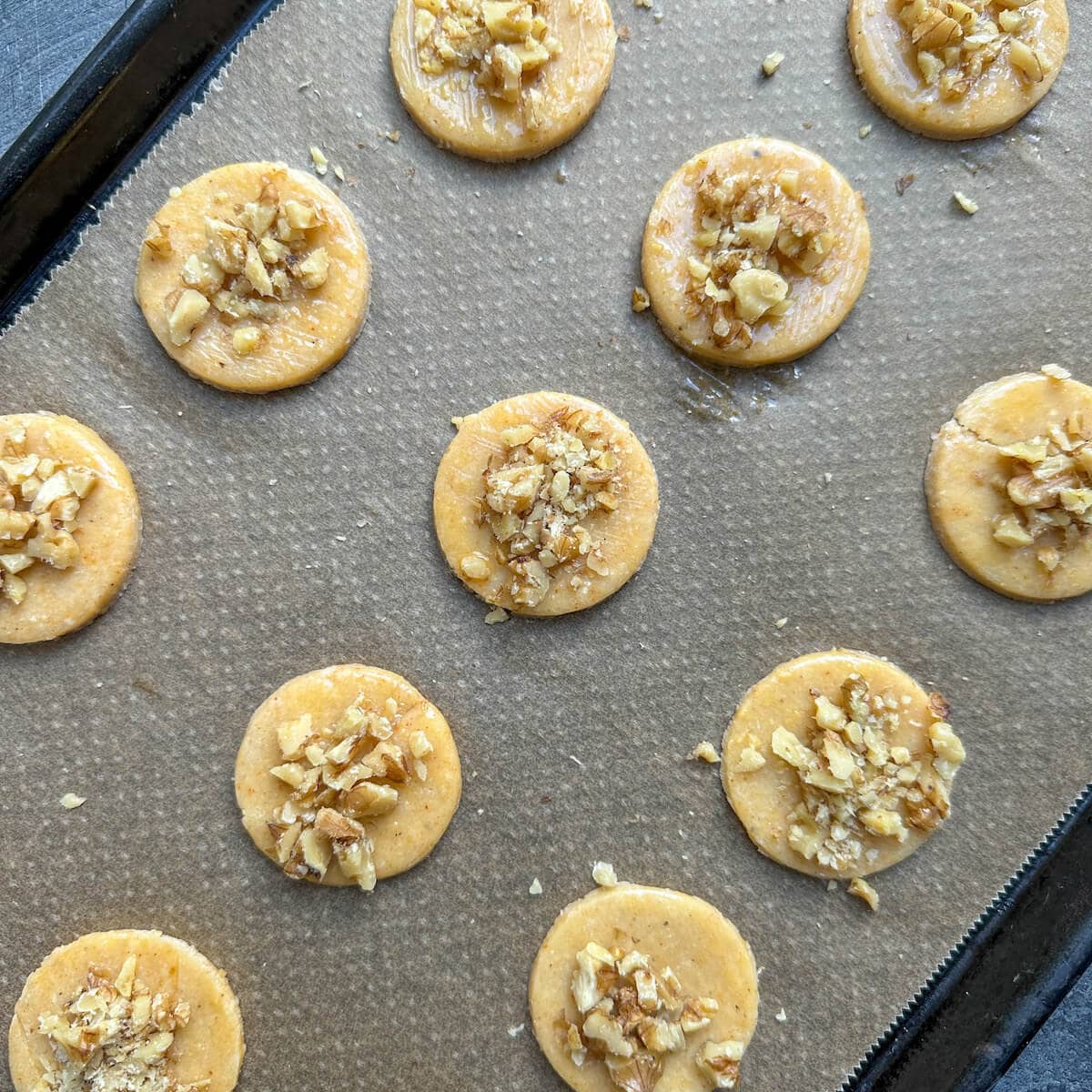 Parmesan sables with chopped walnuts on a baking tray. 