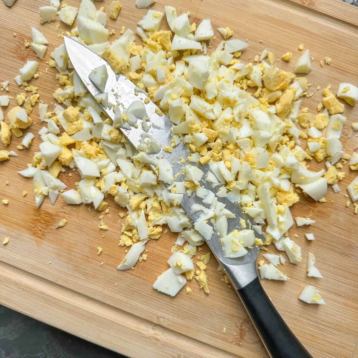 Chopped hard boiled eggs on a wooden board. 