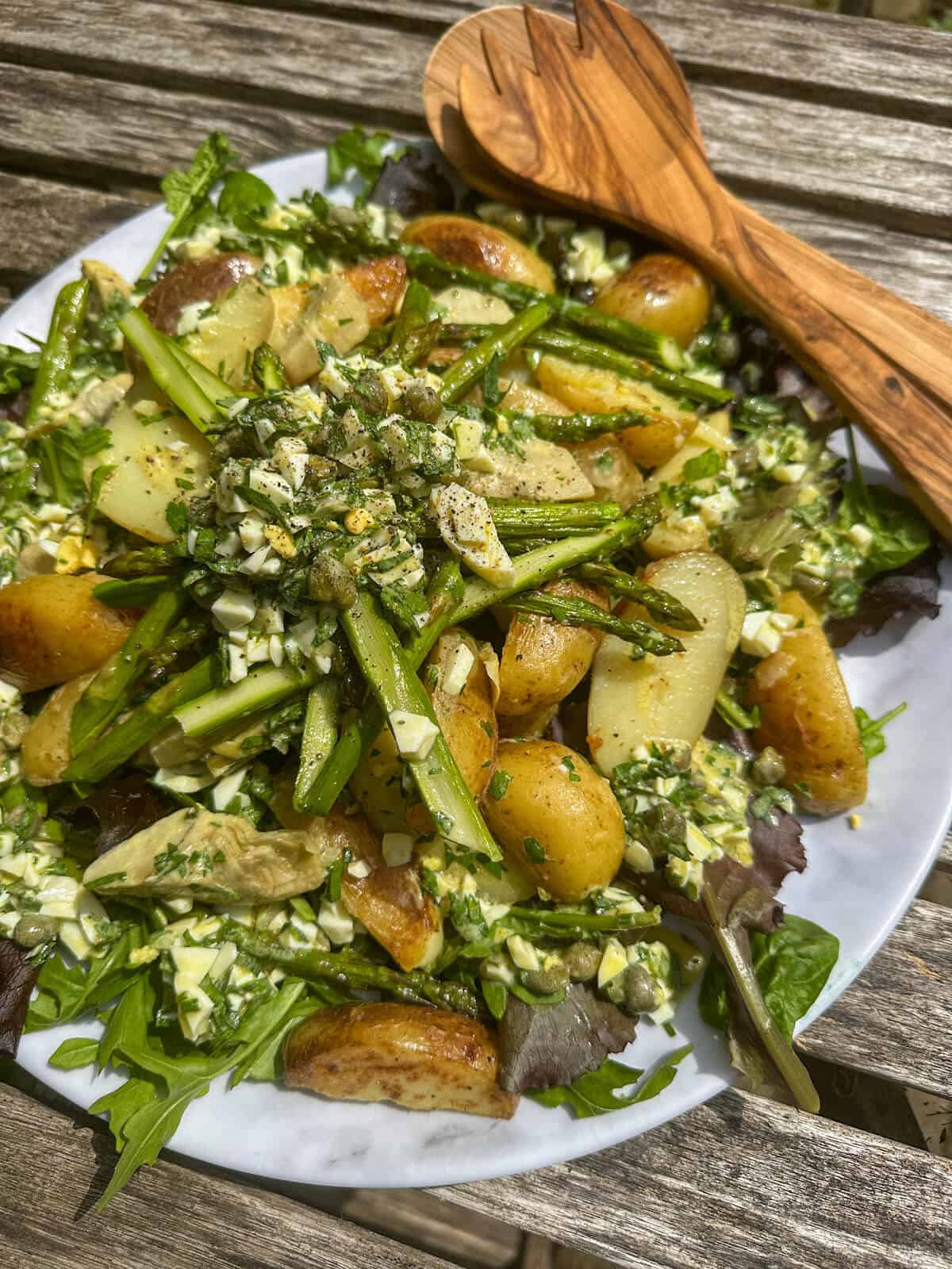 artichoke, potato and asparagus salad with boiled egg vinaigrette on a platter. 
